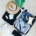 open suitcase with clothes and straw hat