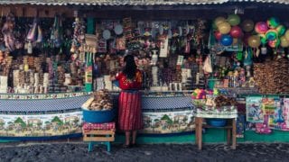 Guatemalan woman stands in front of a crowded market stall