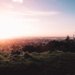 Live in New Zealand: Three people sit on Mt Eden in Auckland at dusk