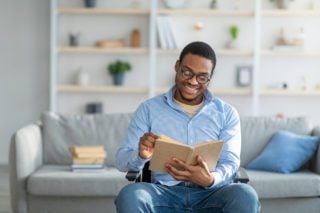 Black man in wheelchair reading book on other cultures
