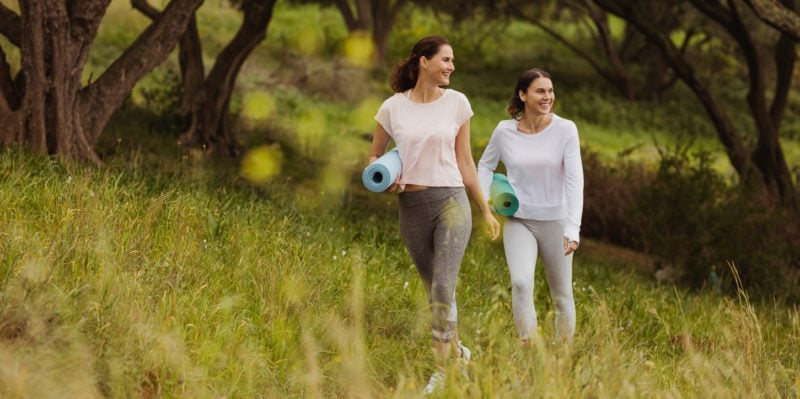 Female friends walking to yoga in the park