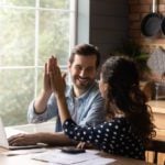 Couple doing budget for a move abroad exchange a high five