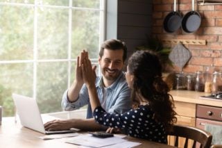 Couple doing budget for a move abroad exchange a high five