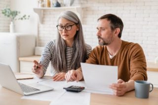 a couple creating a budget on their laptop, having researched expat financial advice for living abroad