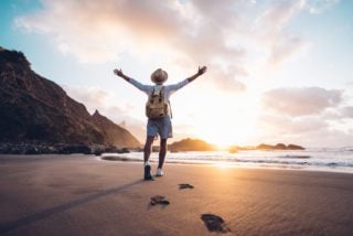 Young man arms outstretched on a beach