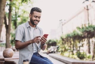 young man reading an expat forum on his cell phone