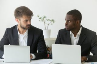 A black employee and a white employee look at each other with skepticism