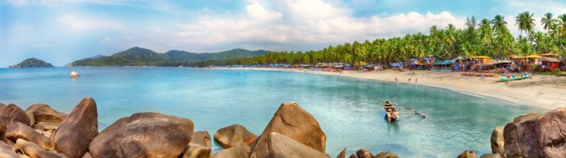 Beautiful Goa province beach in India with fishing boats and stones in the sea