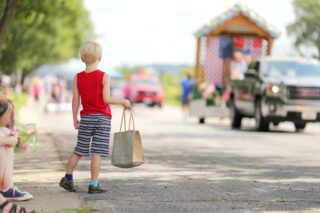 A young boy child standing outside in the summer watching a small town America parade