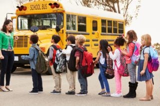 Teacher and a school kids at a bus stop