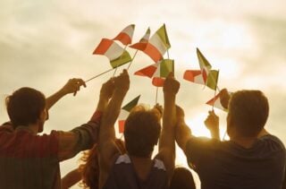 Glowing sun on patriotic Irish citizens holding flags