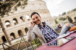 Young businessman sitting at a café in Rome, enjoying a cup of coffee, symbolizing the opportunities for jobs in Italy for Americans