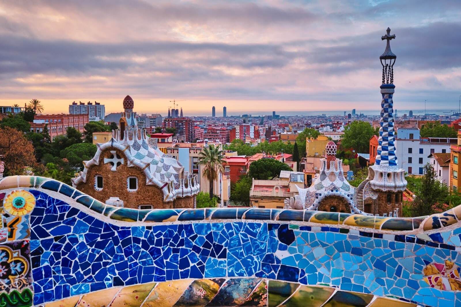 A sunrise view of a colorful mosaic building in Park Guell, Barcelona