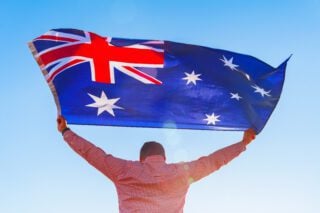 Man with a flag of Australia standing in field
