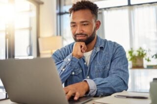 a young man sitting at his laptop applying for a visa as part of his plan for moving to Colombia