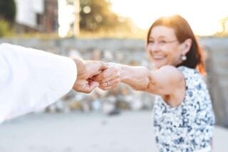 an retired woman smiling and holding her hand out to her partner as she explores one of the best places to retire