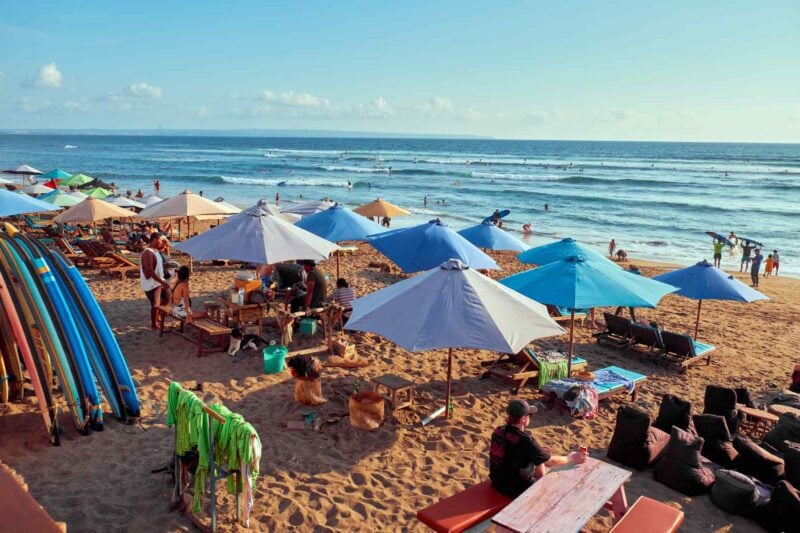 A cluster of colorful beach umbrellas scattered across a beach in Canggu, which has an affordable cost of living in Indonesia