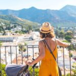 a female expat standing at a lookout, pushing a stroller and admiring a view of Mijas in Malaga, Spain