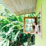 a woman leans from a window in a jungle setting, after moving to Costa Rica from the USA