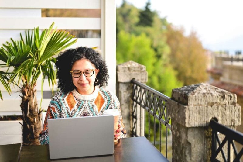 a female digital nomad working on her laptop having secured an Italy work visa