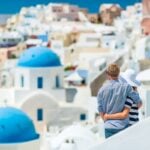 a happy couple looking across the rooftops of Santorini island, after moving to Greece