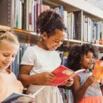 Young children studying abroad, reading books in a school library