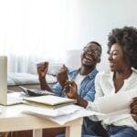a happy couple reading expat financial advice on their laptop at home