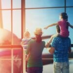 a family with children at an airport looking outside at the place as they prepare for moving abroad