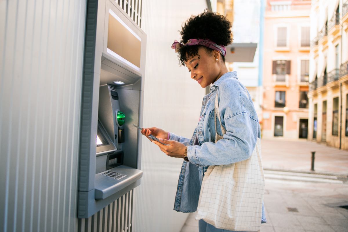 a woman withdrawing money from an ATM machine, after moving abroad and opening a bank account