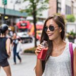 a woman enjoying a cold drink on the go in New York, highlighting the high average cost of living in the U.S.
