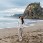 a woman walking along a beach in Auckland, symbolizing the lifestyle and cost of living in New Zealand