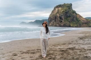 a woman walking along a beach in Auckland, symbolizing the lifestyle and cost of living in New Zealand