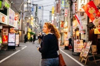 a woman walking through a neon-lit street in Tokyo, one of the best places to live in Japan