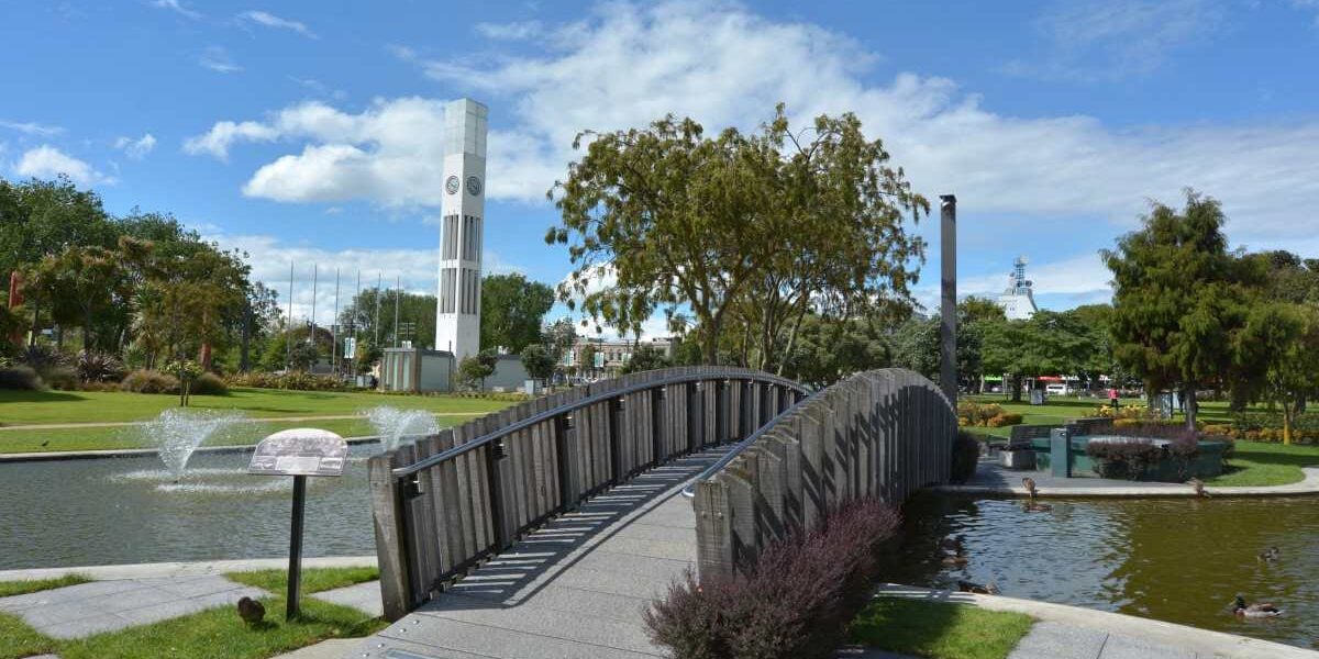 a bridge over a lake in Palmerston North, where the cost of living in New Zealand is affordable